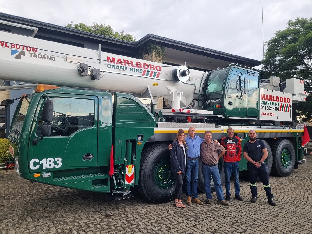 Marlboro Crane Hire officials stand with MMS officials in front of a new Tadano all-terrain crane from a distance.