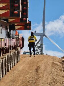 An engineer observes as an SPMT shifts crane counterweights from one wind turbine site to another.